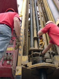 Workers operating drill rig