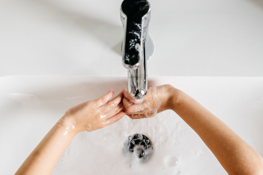 A young boy washes his hands in a bathroom sink.